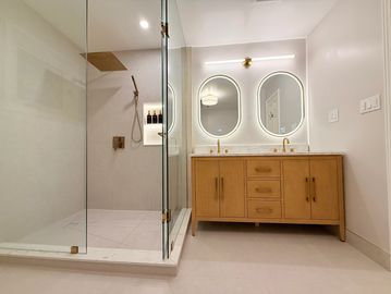 Modern bathroom with glass shower and wooden vanity.