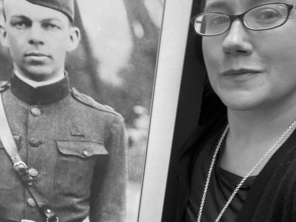 Dr. Chrissie Reilly posing with a framed black-and-white military photo of MAJ Edwin Howard Armstrong, inventor of FM radio. 