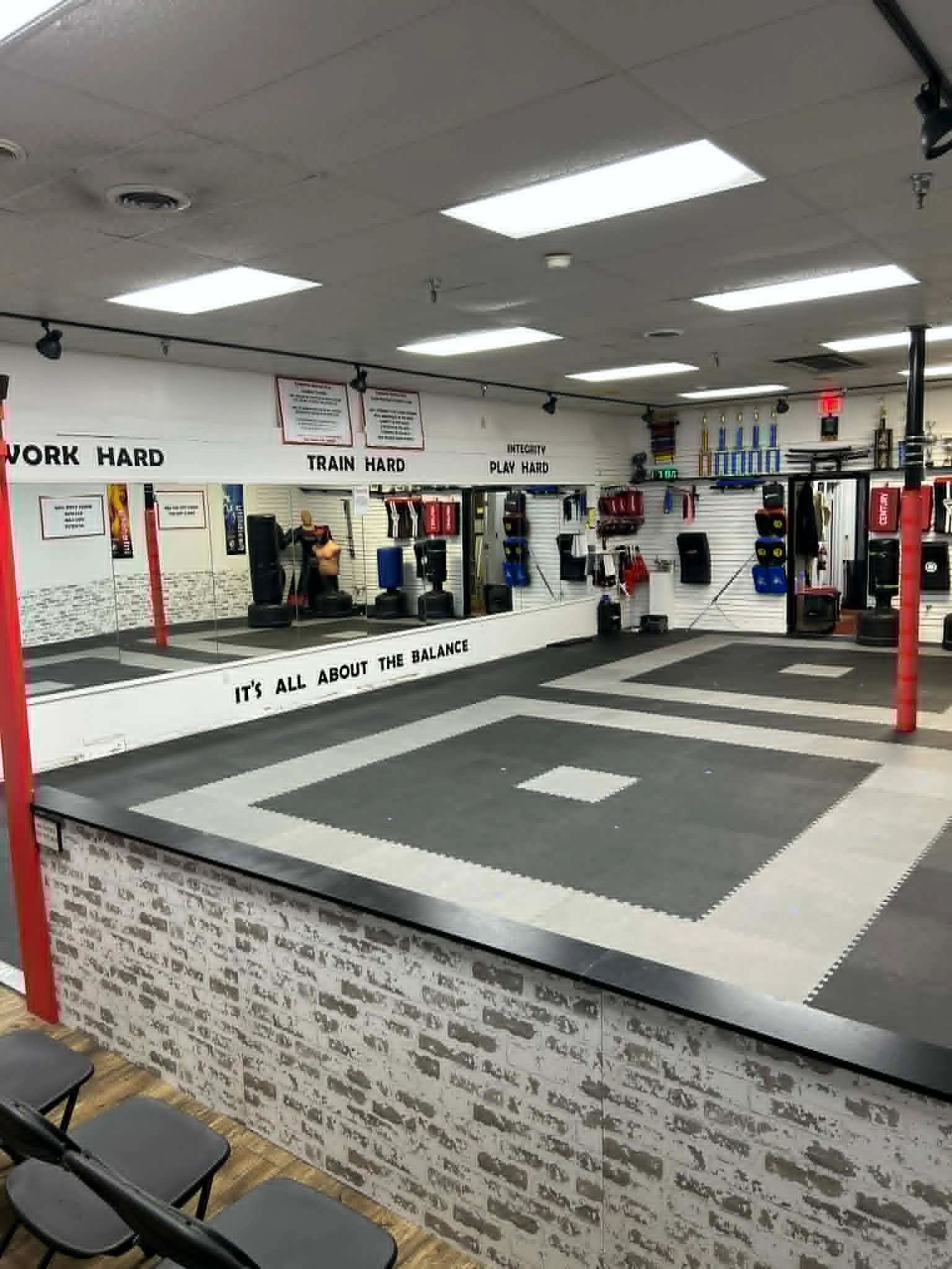 A spacious martial arts training room with motivational quotes on the walls.