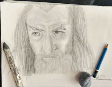 Pencil sketch of a bearded man's face with two pencils.
