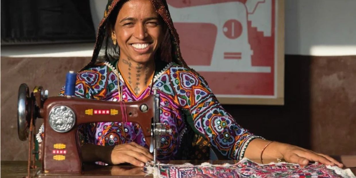 Smiling woman using a sewing machine with vibrant fabric.