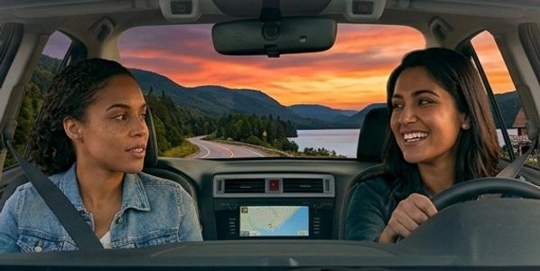 Two women enjoy a scenic drive at sunset with smiles and conversation.