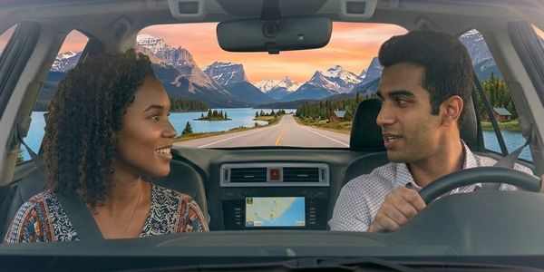 A couple enjoys a scenic mountain drive during sunset.