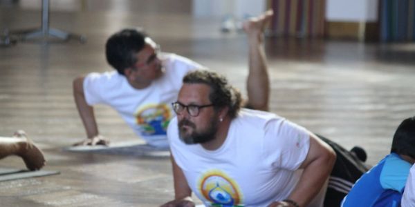 Two men practicing yoga indoors on a wooden floor.