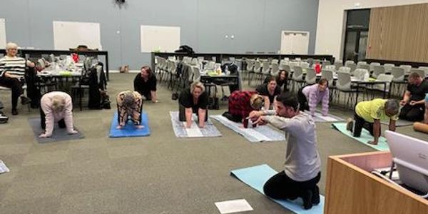 A group yoga class practicing cat-cow pose indoors.