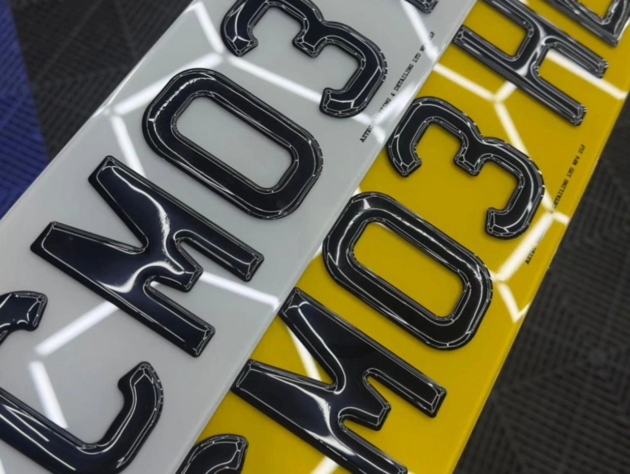 Close-up of black raised letters on white and yellow reflective surfaces.