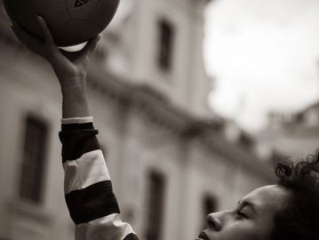 Person holding a basketball up outdoors.
