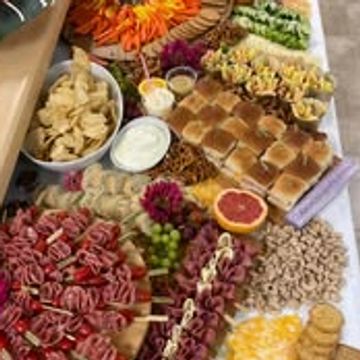 A colorful charcuterie board with meats, cheeses, crackers, and dips.