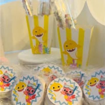 Party favors featuring Baby Shark and friends in yellow-striped bags and round stickers.
