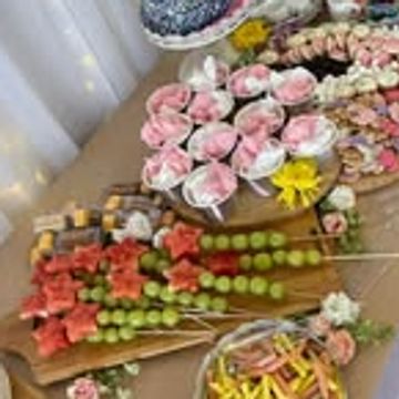 Elegant dessert table with cakes, chocolates, and fruit skewers.
