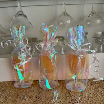 Three iridescent wrapped glasses with straws, decorated with curly ribbons.