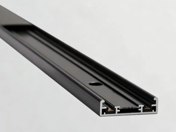 Close-up of a black aluminum extrusion profile with grooves and holes.