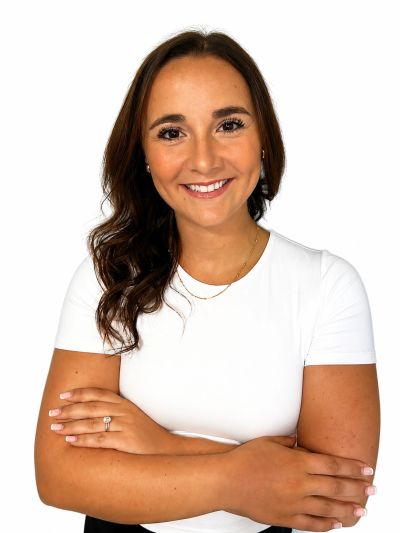 Smiling woman with crossed arms in white top.