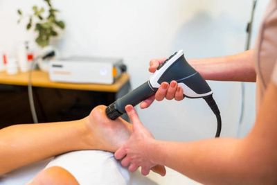 Therapist using device on patient's foot.