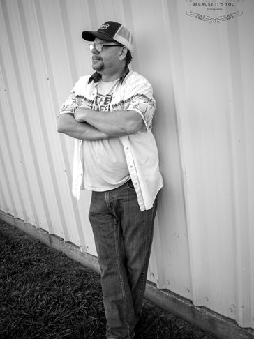 Man leaning against a metal wall, arms crossed.