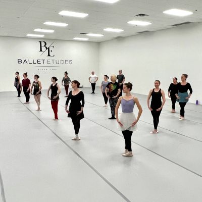 Ballet class with dancers lined up in a spacious studio.