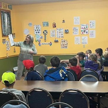 Teacher shows drawing to attentive children in a classroom.