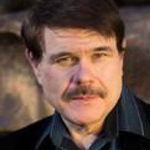 Man with mustache and dark hair looking at the camera.
