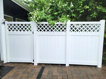 White vinyl privacy fence with lattice top panels in a backyard.
