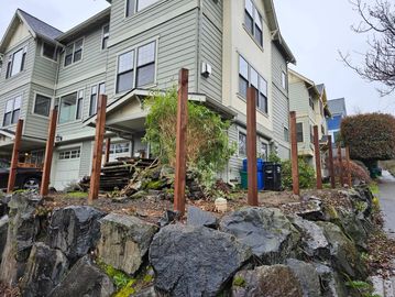 Wooden posts installed around a residential property on a rocky slope.
