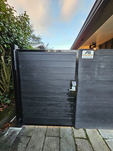 Black wooden gate with a keypad lock and security camera.