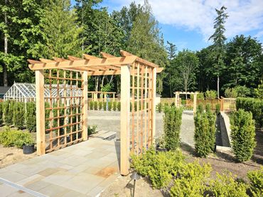 Wooden garden archway with greenery and clear blue sky.