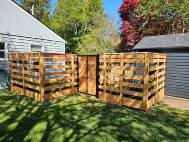 A wooden compost bin with multiple compartments in a backyard.