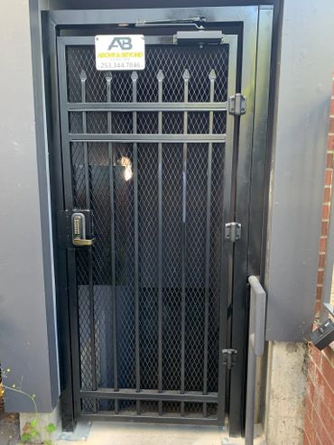Black metal security door with keypad lock and signage above.