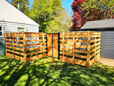 Wooden compost bins in a sunny backyard with greenery.