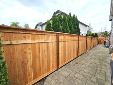 New wooden privacy fence along a paved backyard walkway.