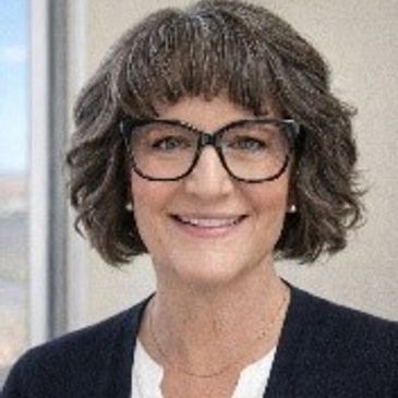 Smiling woman with glasses and curly hair.