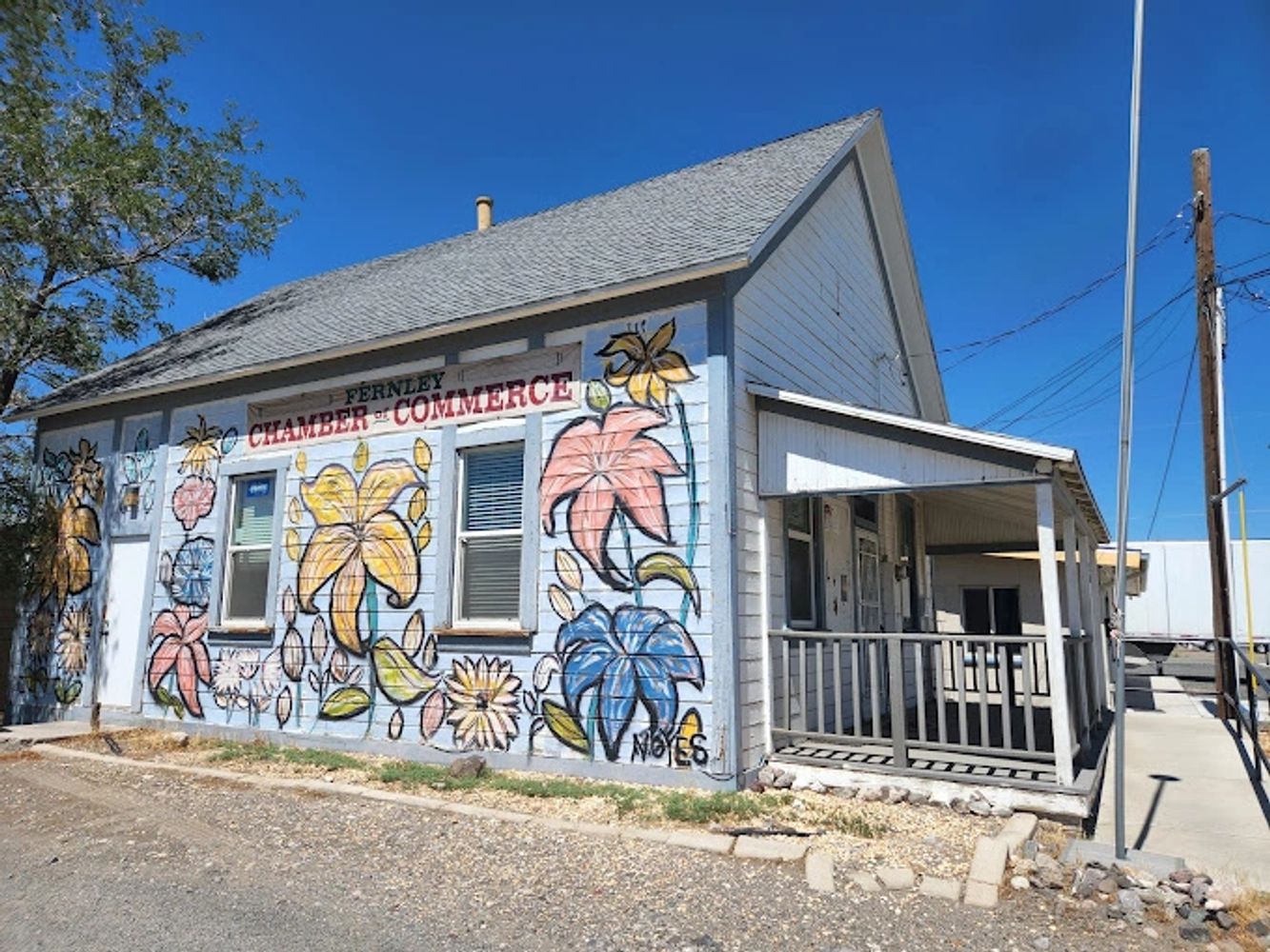 Colorful floral mural decorates the Fernley Chamber of Commerce building on a sunny day.