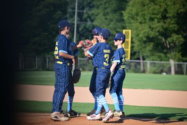 Youth baseball players huddled on the field.
