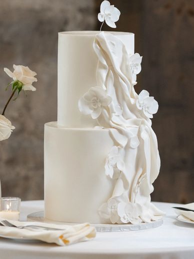 Elegant two-tier white wedding cake with delicate floral decorations.