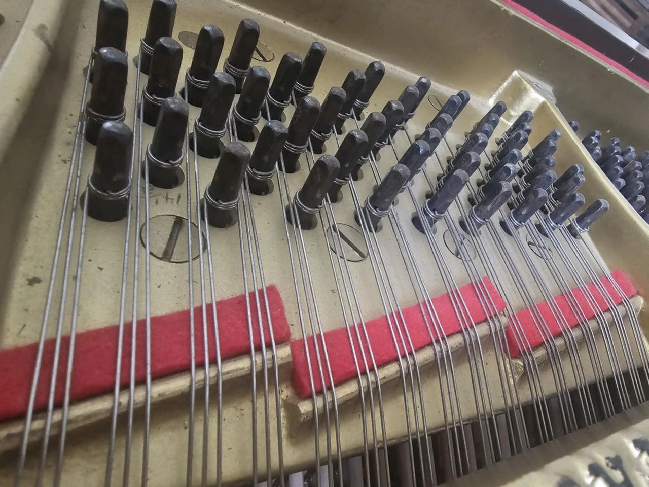 Strings wrapping around tuning pins on a grand piano. 