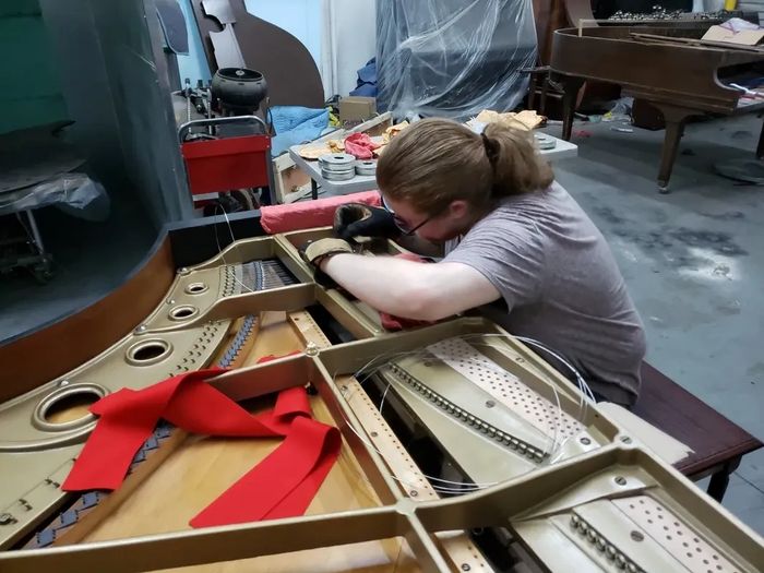 Header photo of piano getting new strings