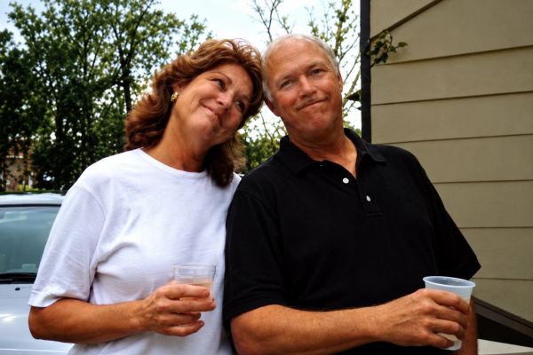 Couple smiling outdoors holding drinks.