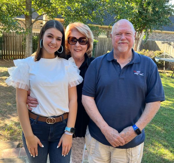 Three people posing outdoors in casual wear.