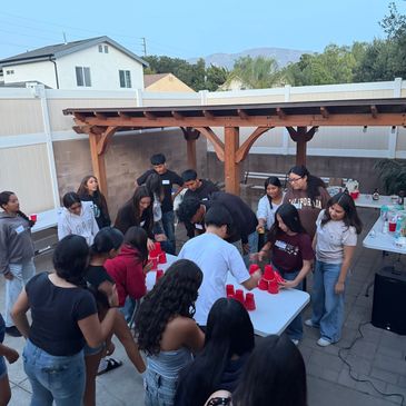 Group of young people playing beer pong outdoors.