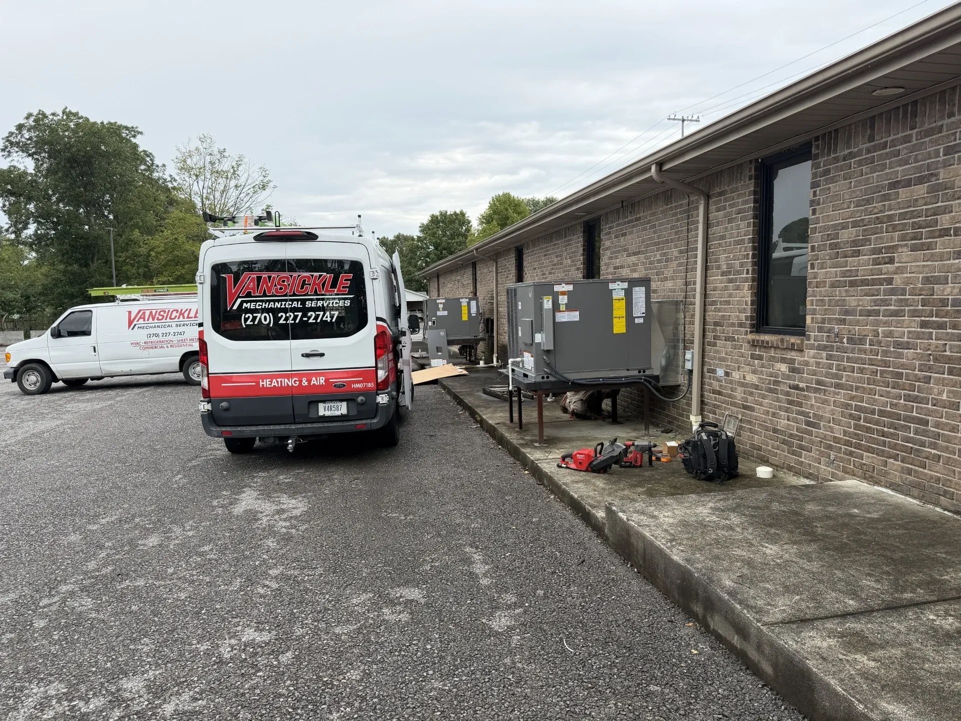 Two Vansickle Mechanical Services vans outside a building with HVAC units.