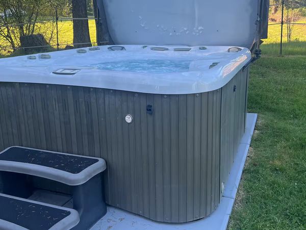 Outdoor hot tub with steps in a backyard.