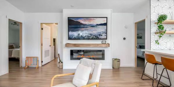 Modern living room with mounted TV and fireplace.