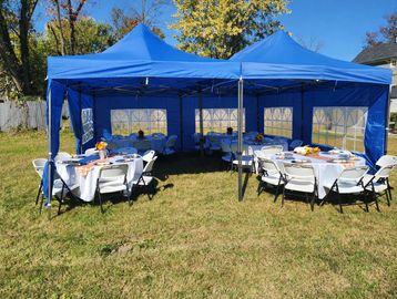 Outdoor event setup with blue tents and round tables.