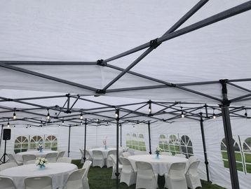 Empty event tent with round tables and chairs set up on grass.