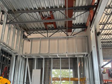 Interior construction with metal framing and exposed ceiling beams.