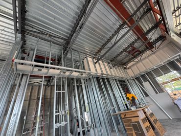 Interior view of a building under construction with metal framing and exposed ceiling.