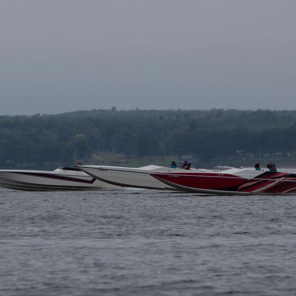Two speedboats racing side by side on a lake under overcast skies.