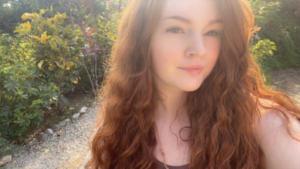 Young woman with long red hair in sunlight.