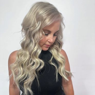 Woman with long wavy platinum blonde hair looking down.