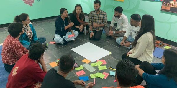 A group of people sitting in a circle discussing ideas with colorful notes.